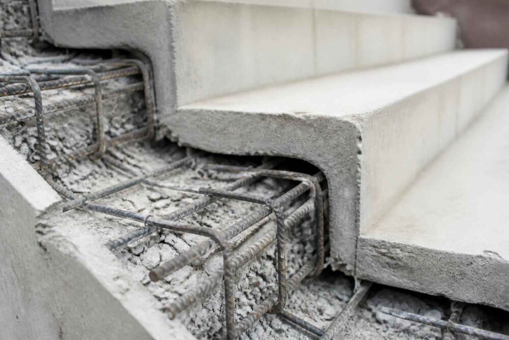 Betonowe stopnie schodów z widocznym stalowym zbrojeniem i prefabrykowanymi elementami konstrukcji